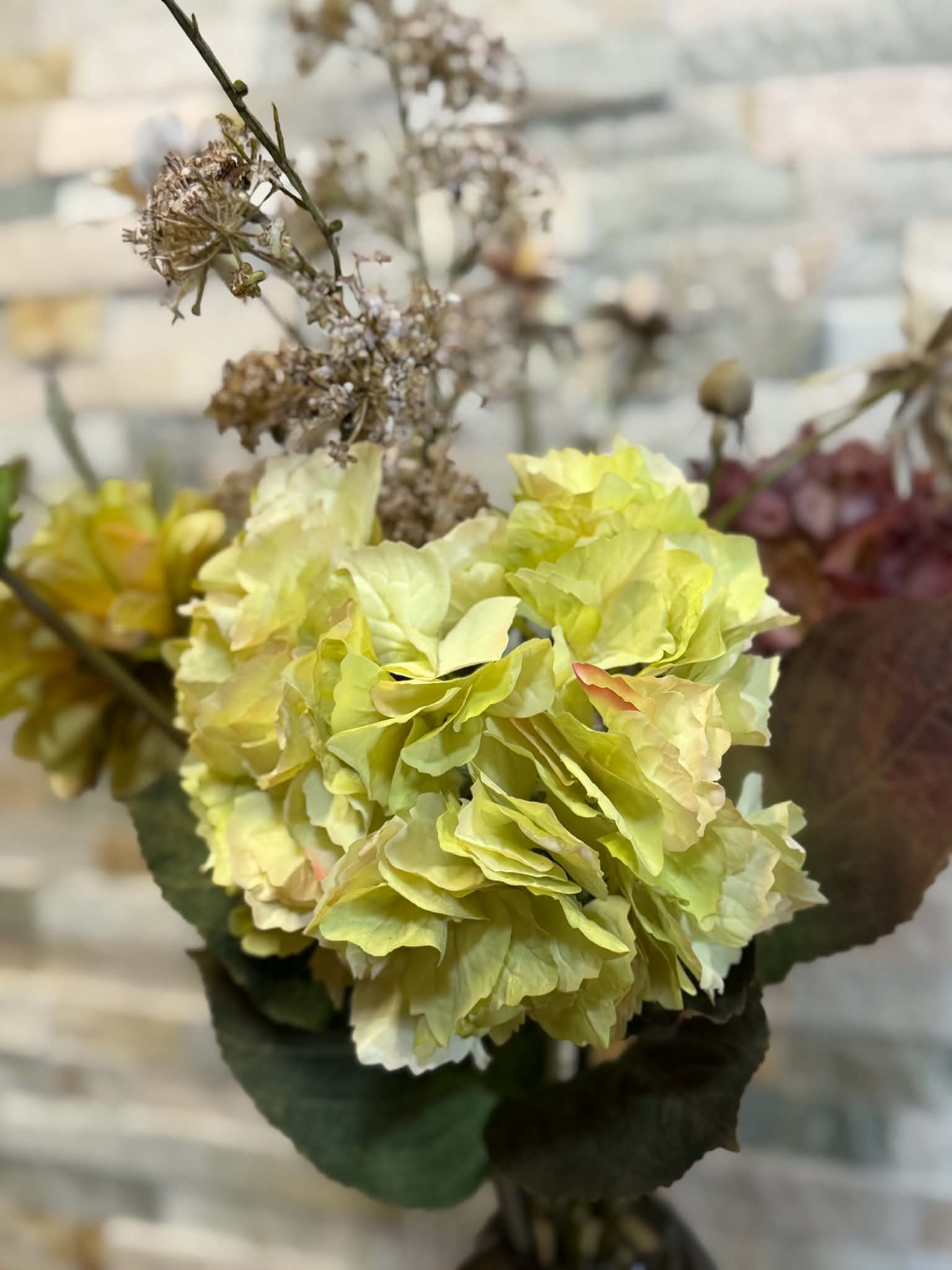 blomsterarrangemang med en stor ljusgrön blomma och mörkröda blommor.