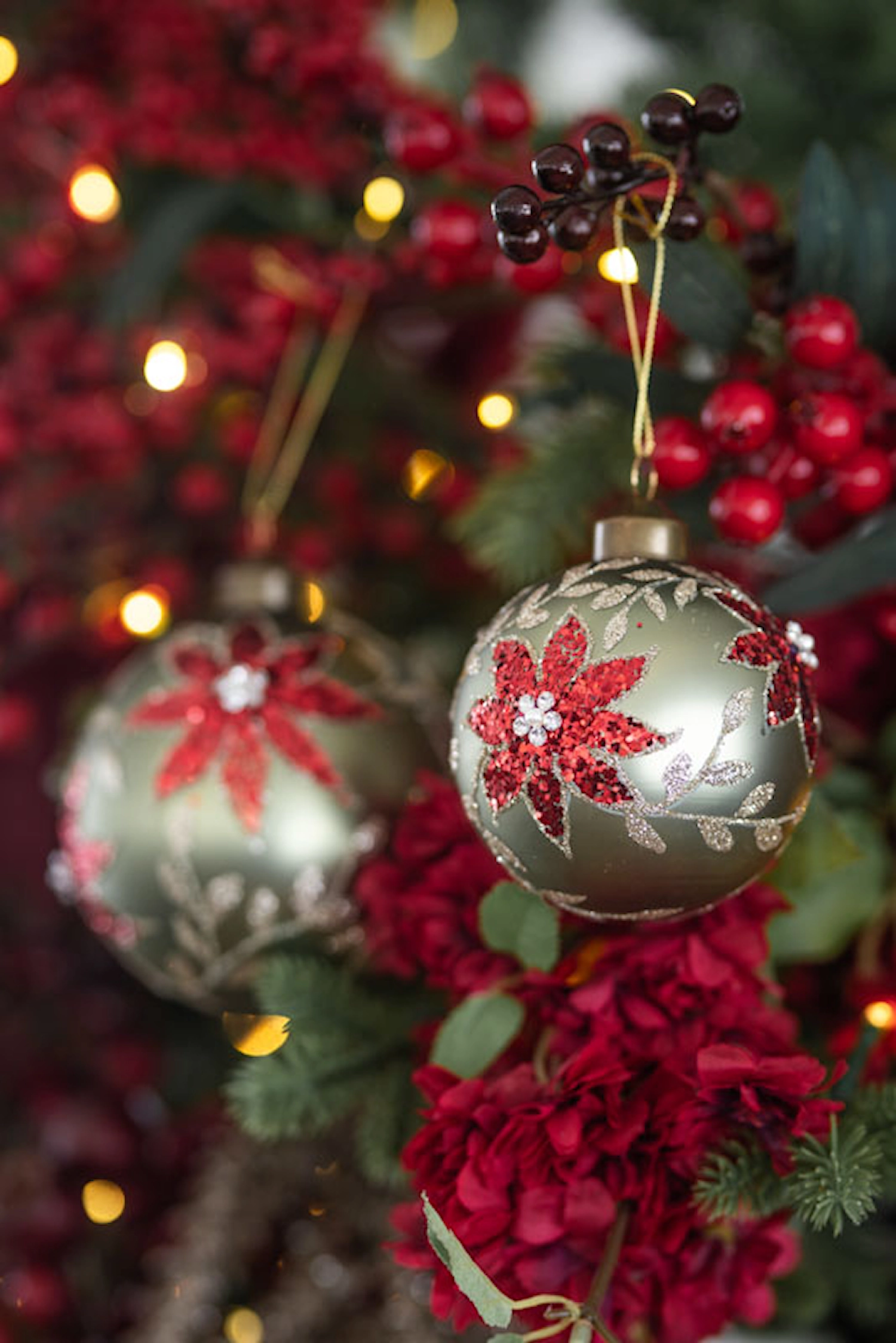 Gröna julkulor med röda julstjärnor i julgran