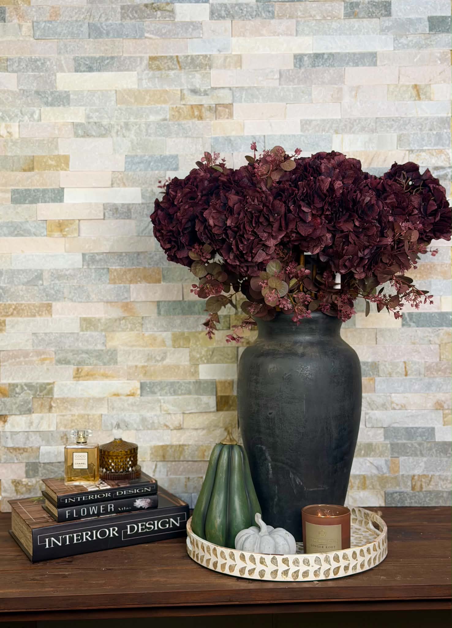 Konstgjord hortensia bordo 70 cm med fylliga vinröda blommor arrangerade i en mörk vas på ett dekorativt bord.